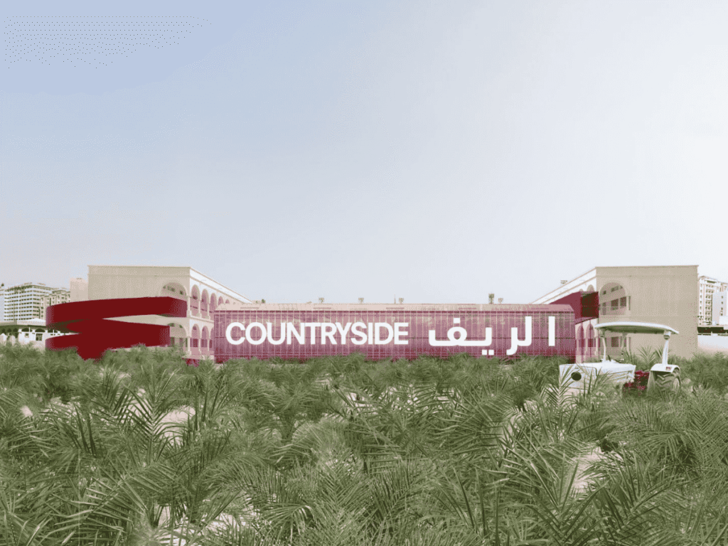 A modern building with COUNTRYSIDE and Arabic text on its facade, surrounded by green palm trees. A small white vehicle is parked to the right, and city buildings are visible in the distant background.
