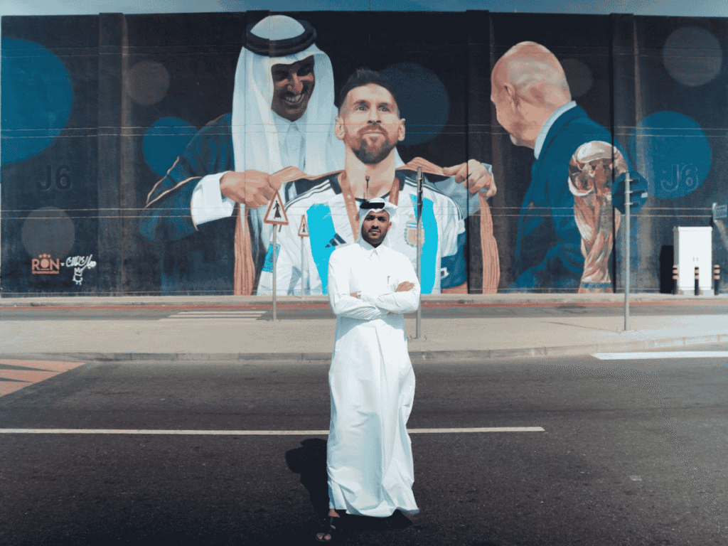 Qatari street artist Mubarak Al Malik in front of the mural he completed with Argentine street artist Martin Ron. Courtesy of Mubarak Al Malik