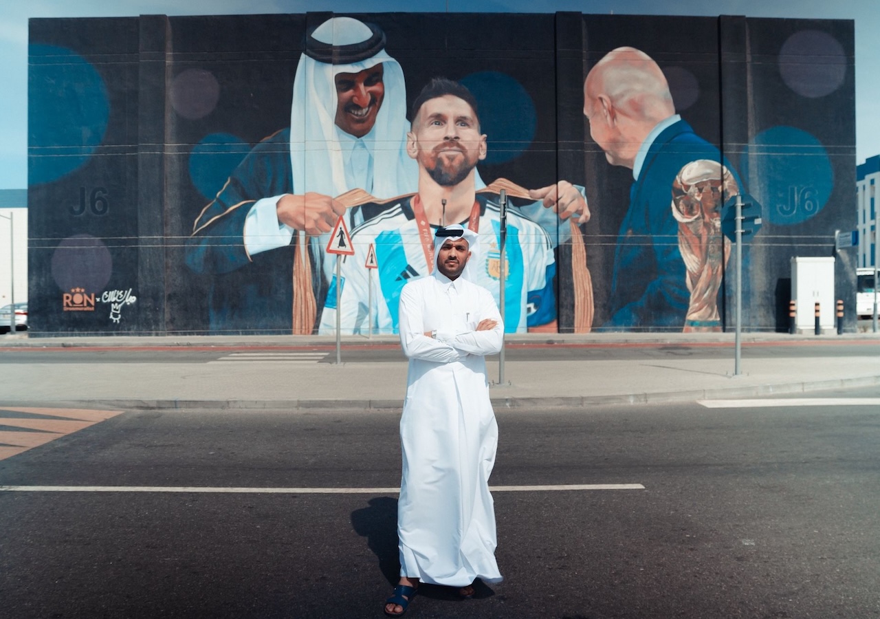Qatari street artist Mubarak Al Malik in front of the mural he completed with Argentine street artist Martín Ron