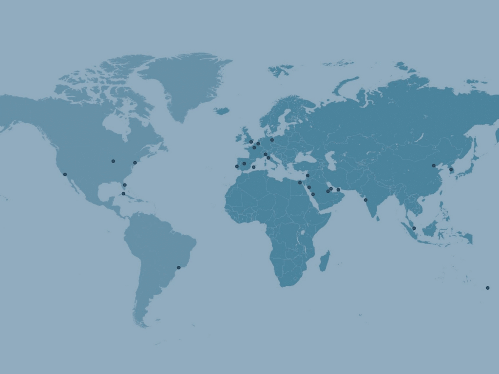 A blue world map with black dots marking various locations across North America, Europe, Africa, and Asia. The background is a lighter blue. There are no labels or text.