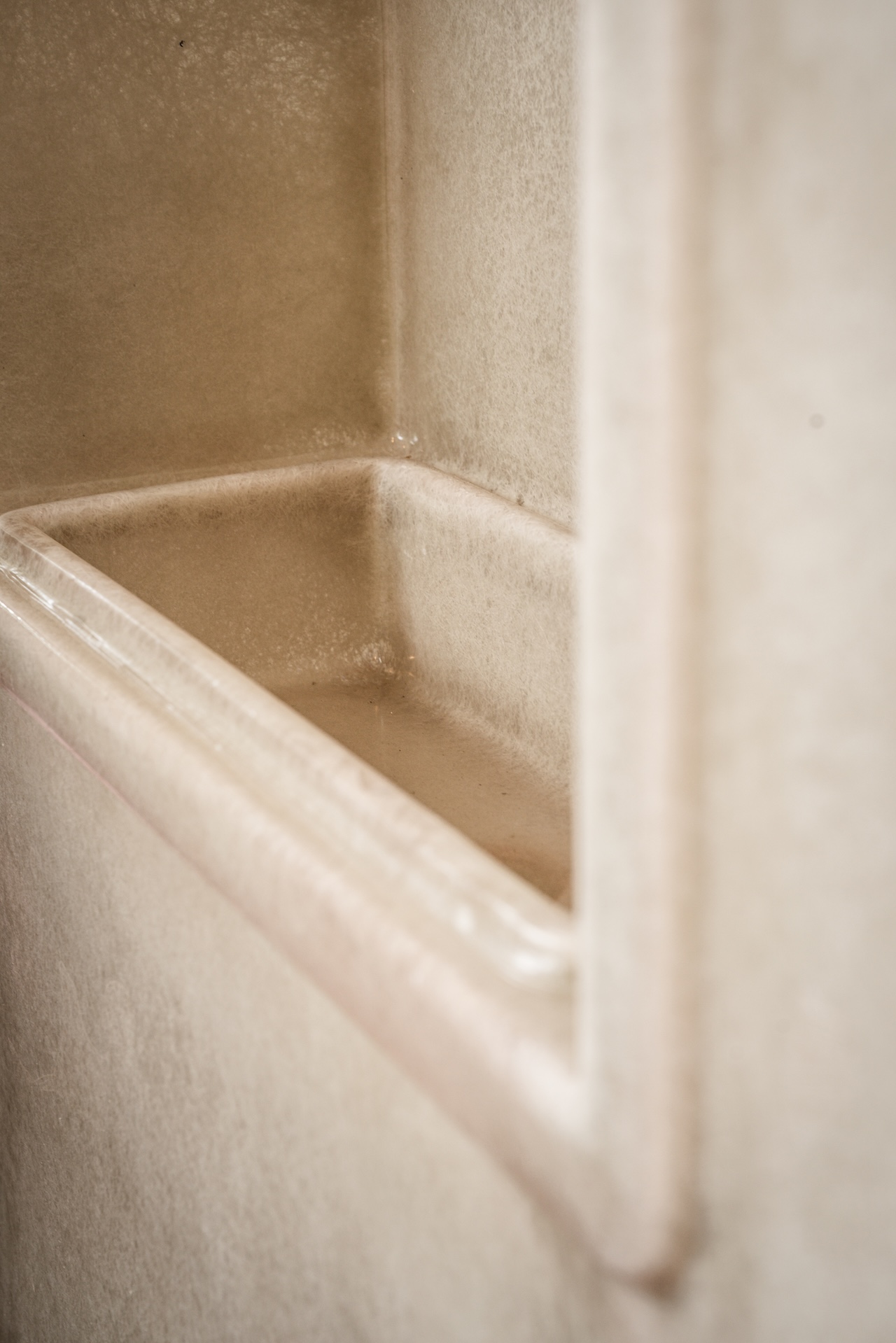 Close-up view of a beige, built-in shower or bath shelf with smooth surfaces and edges, possibly made of fiberglass or acrylic—a minimalist space reminiscent of Fashion Trust Arabia Prize-winning interiors, set seamlessly into the surrounding wall.