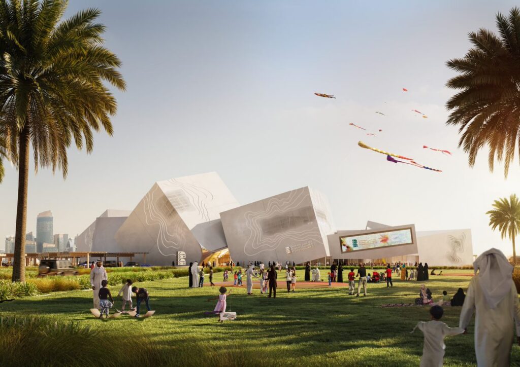People enjoy a sunny day on a grassy lawn with palm trees, children flying kites, and modern white angular buildings in the background under a clear sky