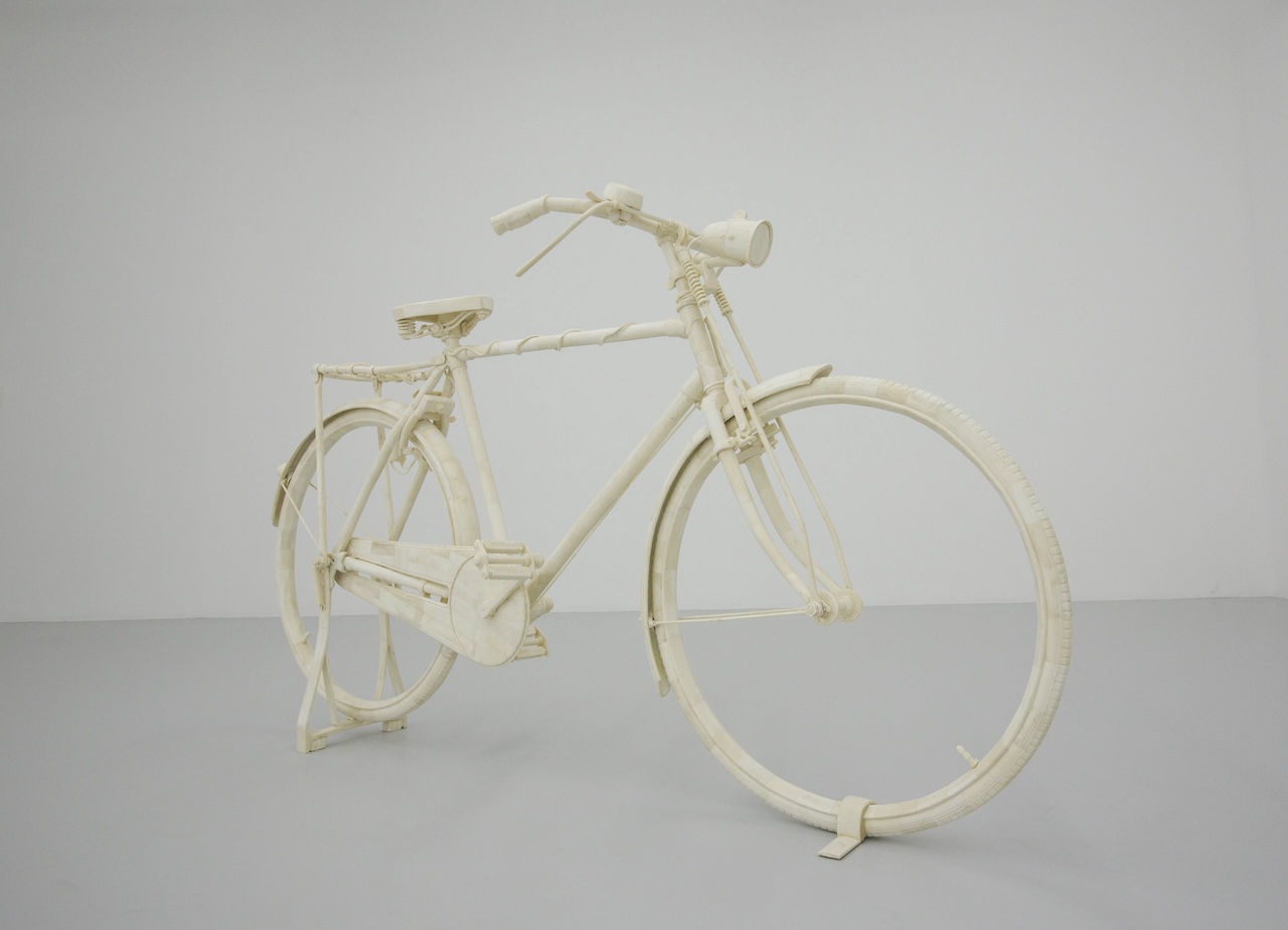 A life-sized bicycle sculpture made entirely of a pale material, possibly paper or tape