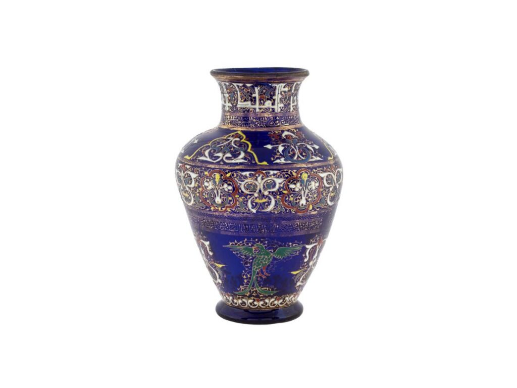 Ornate cobalt blue glass vase in the style of Rirkrit Tiravanija, decorated with colorful floral patterns, calligraphy, and a green bird.