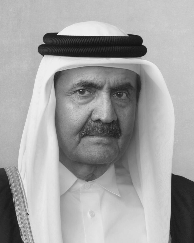 A man wearing a traditional Middle Eastern headdress and robe looks directly at the camera with a neutral expression
