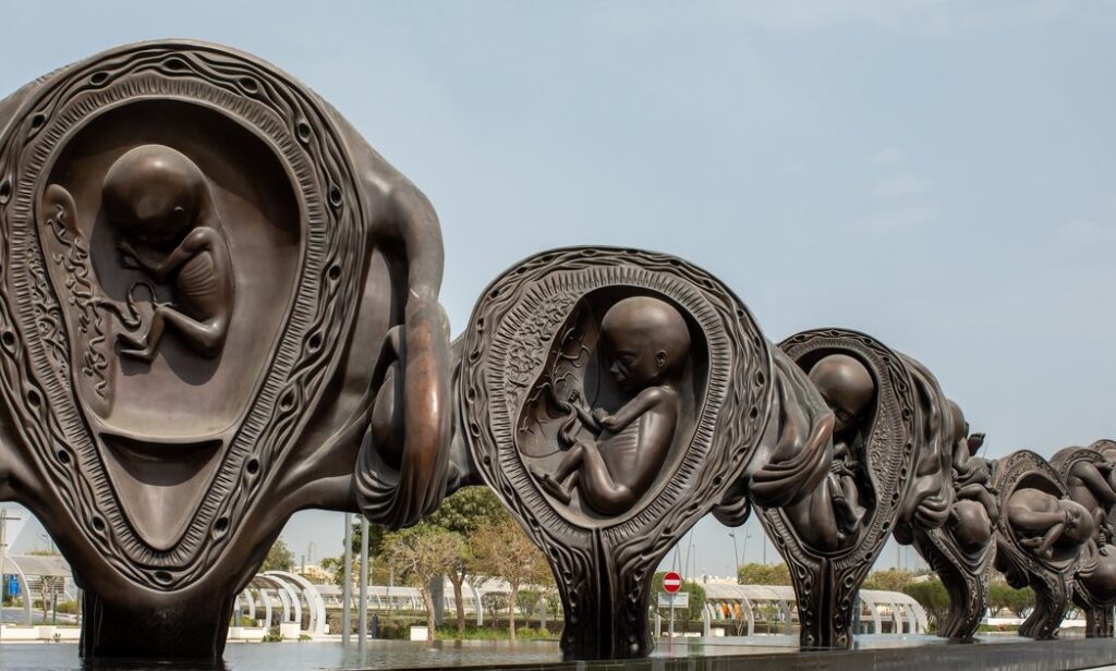 A row of bronze sculptures by Rirkrit Tiravanija depicting fetuses in various stages of development within the womb.