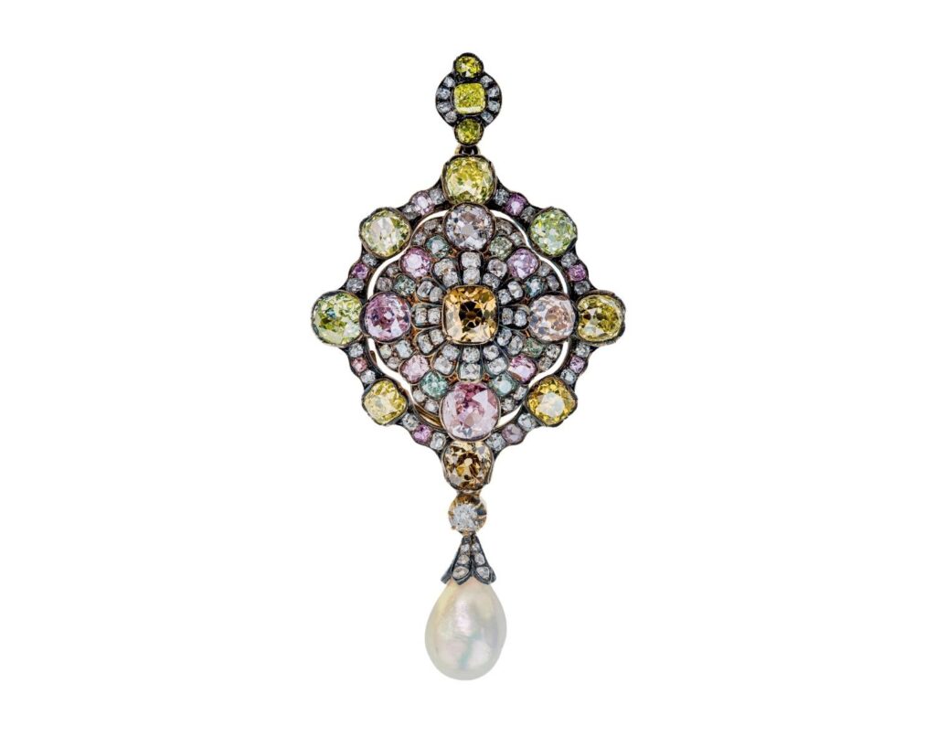 An ornate jewellery pendant featuring a central orange gemstone surrounded by multicolored, circular-cut stones in yellow, pink, and green, with a single teardrop-shaped pearl hanging from the base.