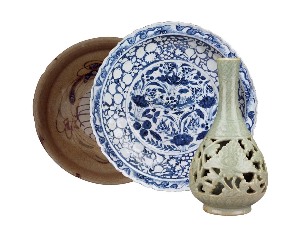 A brown ceramic bowl, a white and blue porcelain plate patterned with boats floating afar, and a light green celadon vase with cut-out floral designs.