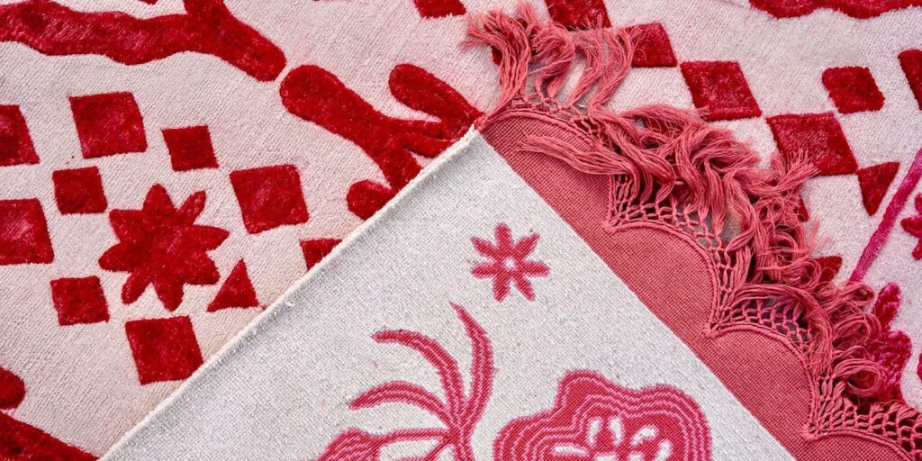 Close-up of a textured pink and red rug with geometric and floral patterns