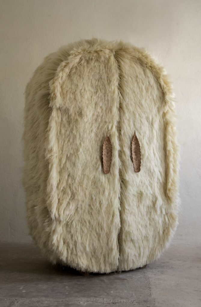 A tall, oval-shaped cabinet covered in shaggy cream-colored fur